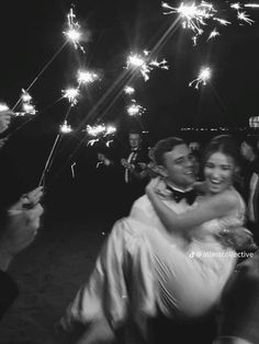 a bride and groom hug as they are surrounded by sparklers at their wedding reception