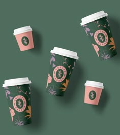 three coffee cups with floral designs on them, one is pink and the other is green