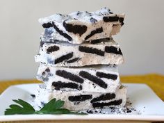 three pieces of ice cream and oreo cake on a white plate with green leaves