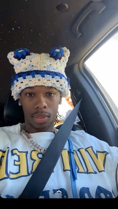 a man sitting in the back seat of a car wearing a hat and holding a pair of scissors