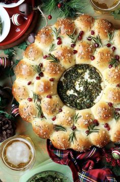 an overhead view of a christmas wreath - shaped bread dish surrounded by other holiday foods