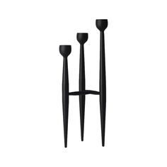 three black candlesticks are standing next to each other on a white background,