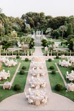 an image of a formal garden setting with tables and chairs set up in the middle