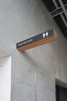 a restroom sign hanging from the side of a building