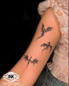 a woman's arm with three dragon tattoos on the back of her left arm