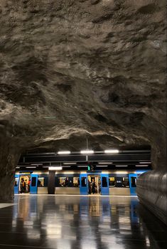 an underground subway station with people waiting for the train to arrive and go in it