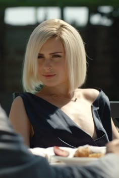 a woman sitting at a table with food in front of her and looking off to the side