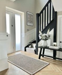 a white vase filled with flowers sitting on top of a wooden floor next to a stair case