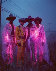 three men in costume standing next to each other with lights on their bodies and hats