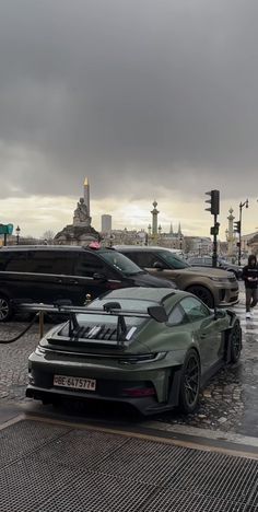 some cars are parked on the side of the road in front of other cars and people