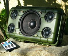 a speaker sitting on top of a rock next to a remote control