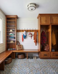 a wooden bench sitting under a window next to a coat rack