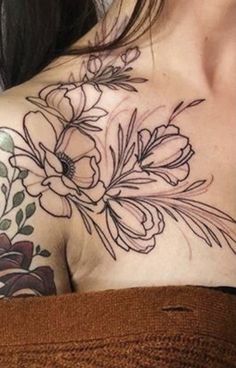 a woman's shoulder with flowers and leaves tattoo on her chest, in black ink