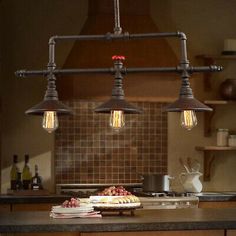 three lights hanging over a kitchen island in front of a stove top oven and counter