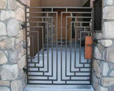 an iron gate is open in front of a stone wall with a wooden door on the other side