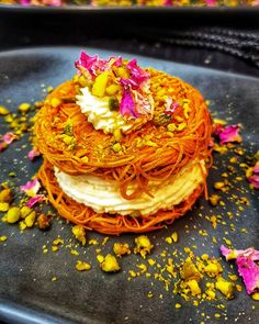 a stack of pancakes covered in flowers and sprinkles on top of a black plate