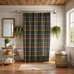 a plaid shower curtain in a bathroom next to a toilet and window with potted plants