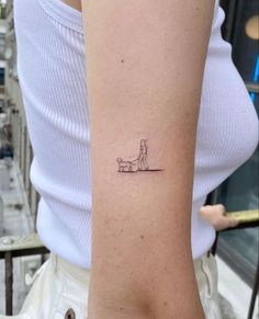 a woman's arm with a small tattoo of a person sitting on a bench