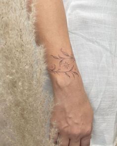 a woman's hand with a small tattoo on her left wrist and the other arm