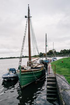 a boat is docked at the dock in the water next to some other boats on the shore