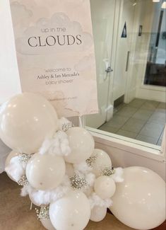 white balloons are on display in front of a sign that says up in the clouds