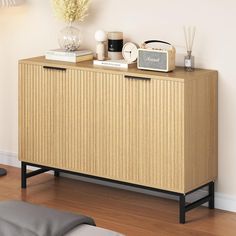 a wooden sideboard with two drawers and an alarm clock on top, next to a bed