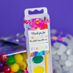 a plastic container filled with lots of colorful candies next to a purple wall and candy