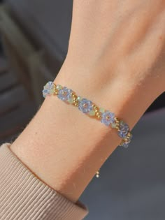 a woman's hand wearing a bracelet with blue beads and yellow glass beads on it