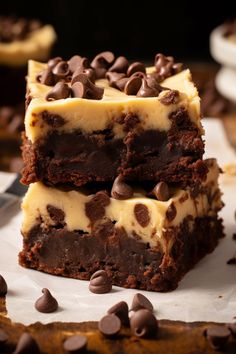 two pieces of chocolate cheesecake brownies stacked on top of each other with chocolate chips