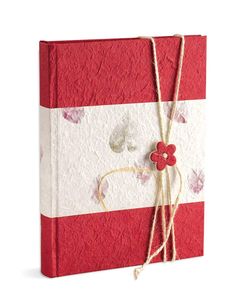 a red and white striped book with flowers on the front, tied in twine