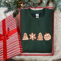 a green shirt with gingerbreads and christmas decorations on it next to a gift box