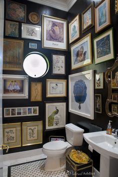 a black and white bathroom with lots of framed pictures on the wall above the toilet