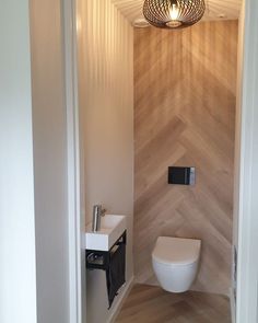 a white toilet sitting inside of a bathroom next to a wall mounted faucet