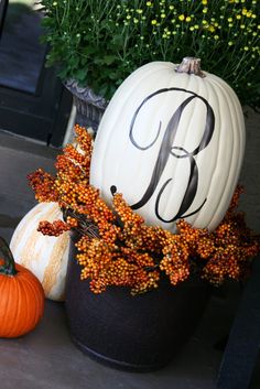 pumpkins and gourds with the letter b on them sit in front of a house