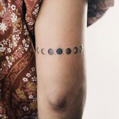 a woman's arm with phases of the moon tattooed on it