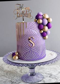 a purple and gold birthday cake sitting on top of a table