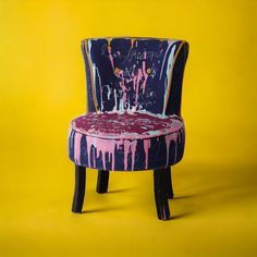 an upholstered chair with paint splattered all over it on a yellow background