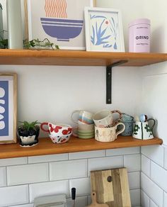 the shelves in the kitchen are filled with cups and bowls, pots and spoons