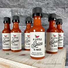 six bottles of hot sauce sitting on top of a wooden table