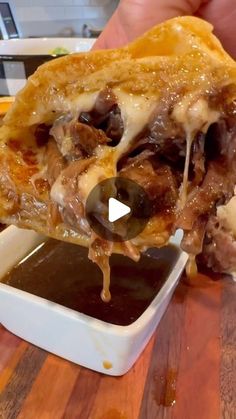 a person is dipping sauce on food in a bowl and holding it up to the camera