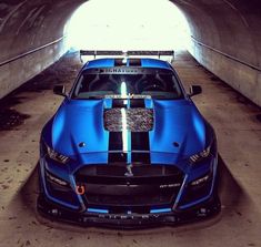 a blue sports car parked in a tunnel with its hood up and the lights on