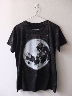 a black t - shirt with the moon on it hanging from a hanger in front of a white wall