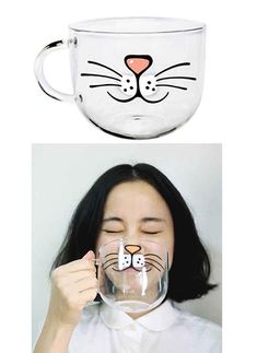 a woman holding a glass cup with a cat's face painted on the side