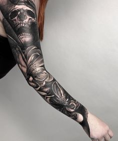 a woman's arm with a skull and flowers tattoo on the left arm,