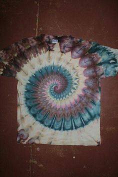 a tie - dyed t - shirt is laying on top of a brown tablecloth