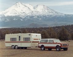 an rv parked next to a truck with a mountain in the background