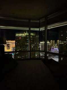 a room with a view of the city lights at night from it's floor to ceiling windows