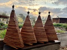 three wooden cones with stars on them are sitting in the grass near some buildings and trees