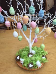 an easter tree is decorated with eggs and moss on a table in front of other decorations