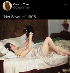 a woman laying on top of a bed next to a cat